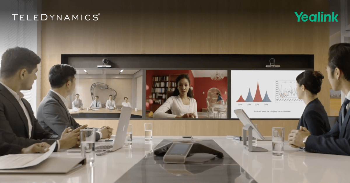 Employees sitting at a conference table during a Yealink-enabled videoconference - Yealink distributed by TeleDynamics