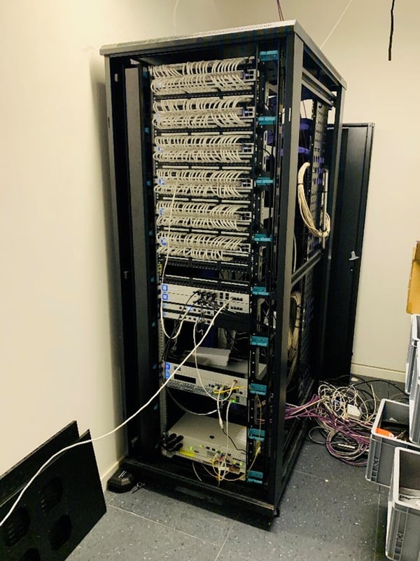 A rack housing patch panels and network devices within a telecom closet - TeleDynamics blog