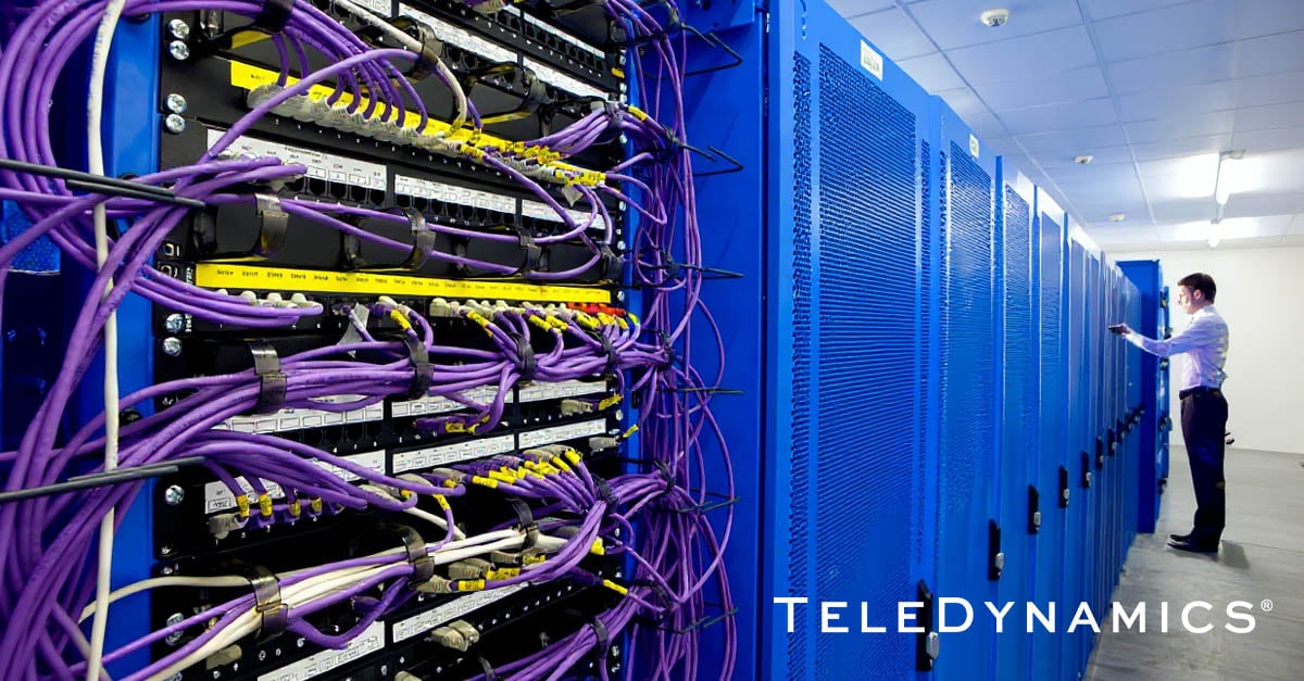 Engineer in data center with close-up of rack cabling -- TeleDynamics blog