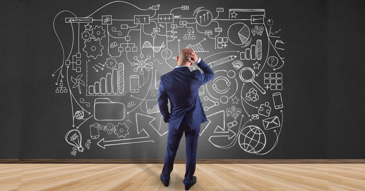 man in front of a chalkboard with a drawing showing complexity