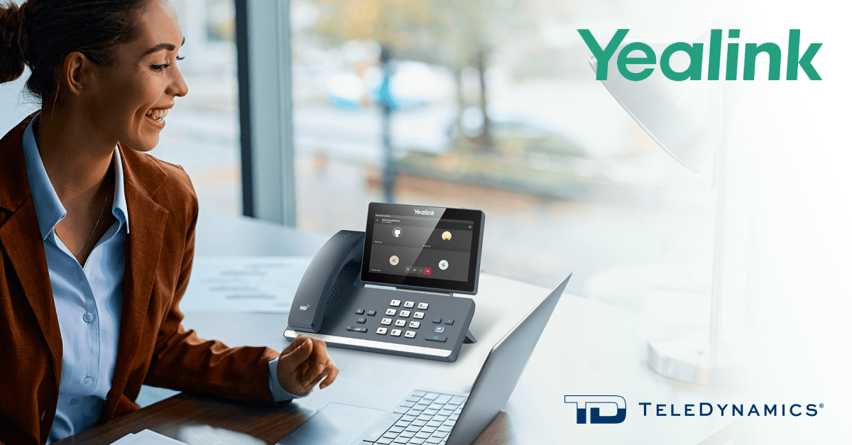 Businesswoman at a desk with a Yealink Teams phone - distributed by TeleDynamics