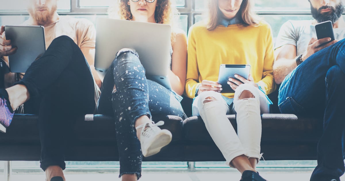 people on a bench using  Wi-Fi with different devices