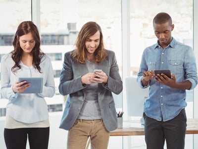 People using connected devices simultaneously in an office - TeleDynamics blog