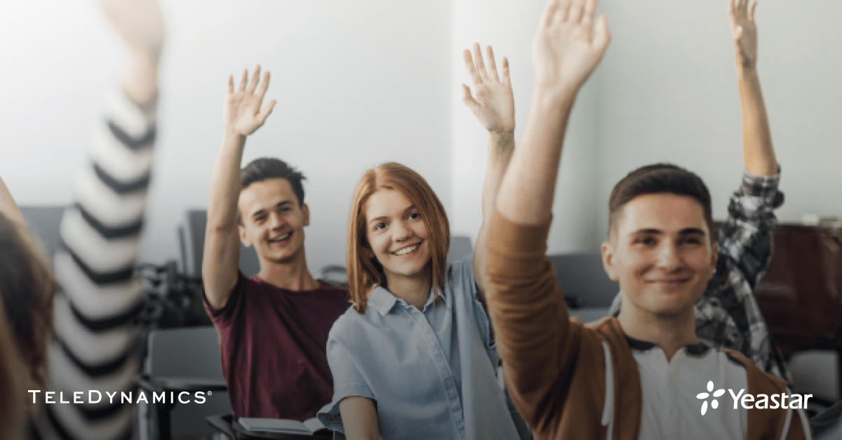 students raising their hands in a classroom - TeleDynamics blog